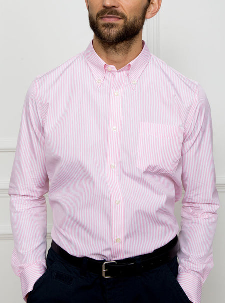 Man wearing a long sleeved shirt with a pale pink and white thin stripe pattern made with 100% Oxford in a Thomas Mason fabric.